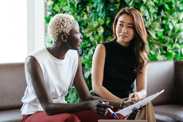 two people sitting on a couch looking over a document